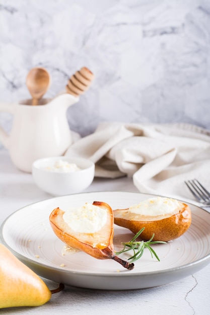 Gebackene Birnen mit Ricotta-Honig und Nüssen auf einem Teller auf dem Tisch Hausgemachtes Dessert vertikale Ansicht