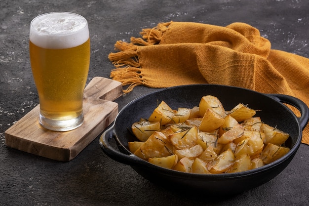 Gebackene Bratkartoffeln mit Rosmarin, grobem Salz, Olivenöl und Gewürzpaprika in einer Eisenpfanne und einem halben Liter Bier