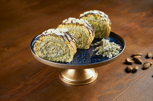 Gebackene Brötchen mit Halva und Mandeln auf einem blauen Teller auf einem Holztisch. Türkische Süßigkeiten. Tee oder Kaffee backen