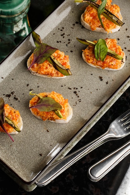 Foto gebackene bruschetta mit lachskäse, sonnengetrockneten tomaten und avocado in grauer platte auf hellem hintergrund