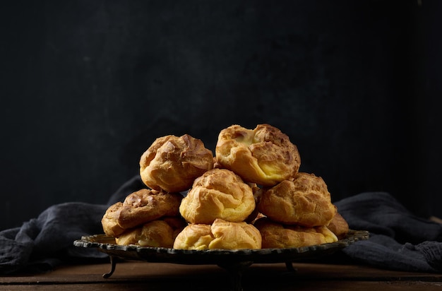 Gebackene Eclairs mit Puddingcreme auf einer runden Metallplatte