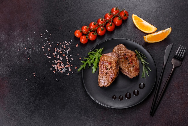 Gebackene Entenbrust mit Kräutern und Gewürzen auf einem dunklen Tisch. Gebratenes Fleisch verzehrfertig