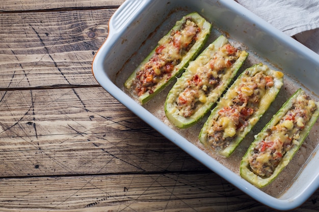 Gebackene gefüllte Zucchiniboote mit gehackten Hühnerpilzen und Gemüse mit Käse auf einem Backblech. Draufsicht Speicherplatz kopieren