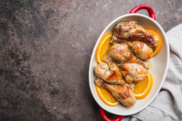 Gebackene Hähnchenkeule in einer Schüssel mit Orange und Rosmarin, Ansicht von oben