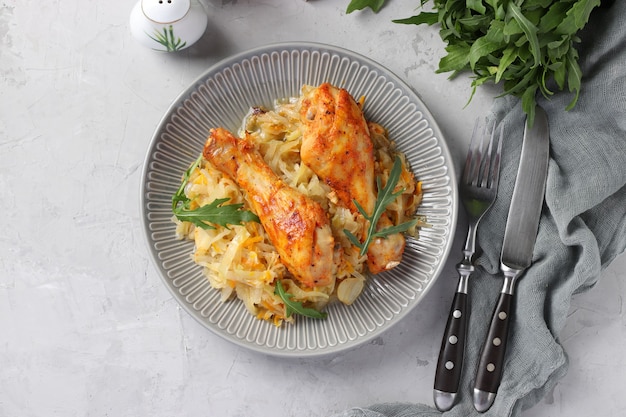 Gebackene Hähnchenkeulen mit Kohl und Knoblauch auf grauem Teller