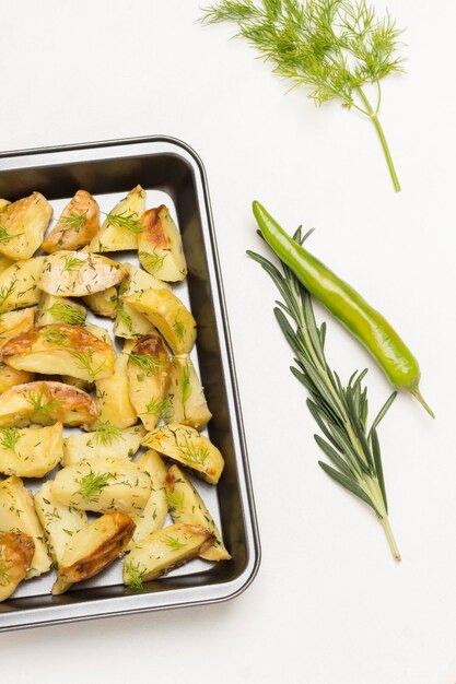 Foto gebackene kartoffeln in einem backgeschirr rosmarin und grüne paprika knoblauch und zitrone auf dem tisch