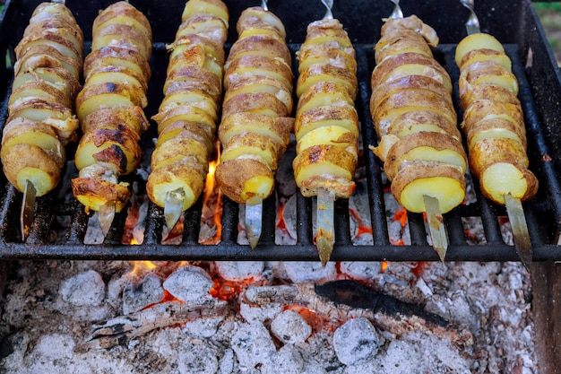 Gebackene Kartoffelscheiben am Spieß auf dem Grill mit Feuer.