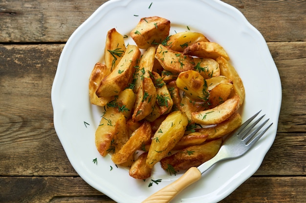 Gebackene Kartoffelscheiben mit frischem Dill auf einem weißen Teller