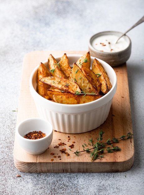 Gebackene kartoffelschnitze mit soße auf hellem hintergrund