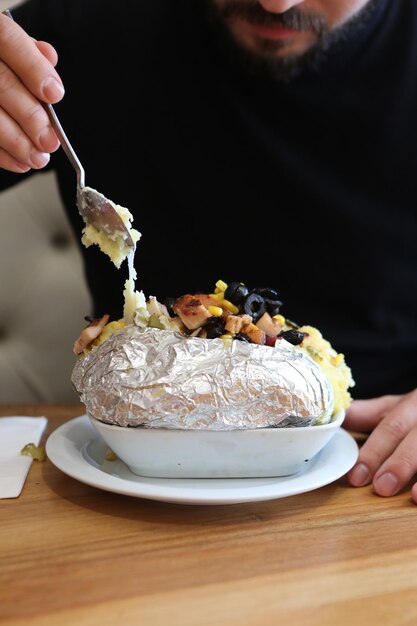 Gebackene Kumpirkartoffel gefüllt mit Käse, Wurst, Oliven, Paprika und Mais