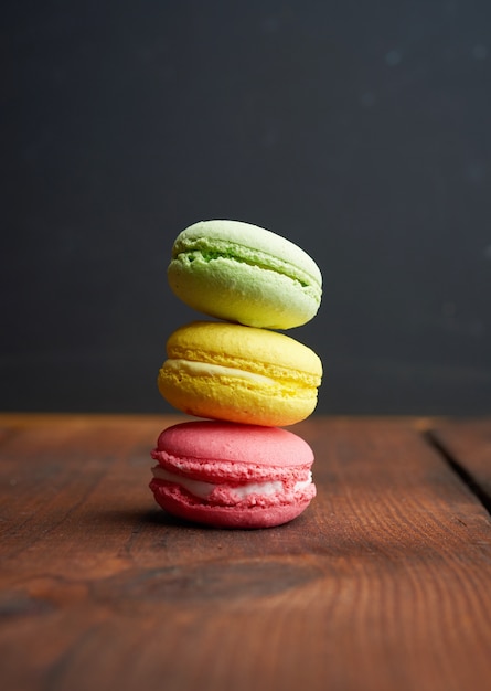 Gebackene mehrfarbige Macaronsplätzchen auf einem braunen hölzernen Hintergrund, nah oben