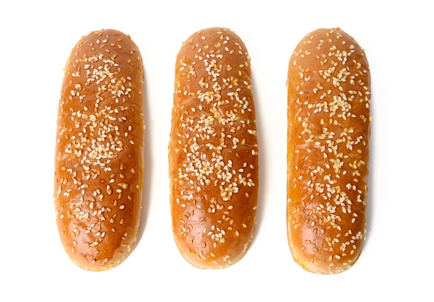 Gebackene ovale Hot-Dog-Brötchen, Backwaren mit Sesam bestreut und isoliert auf weißer Oberfläche, Draufsicht