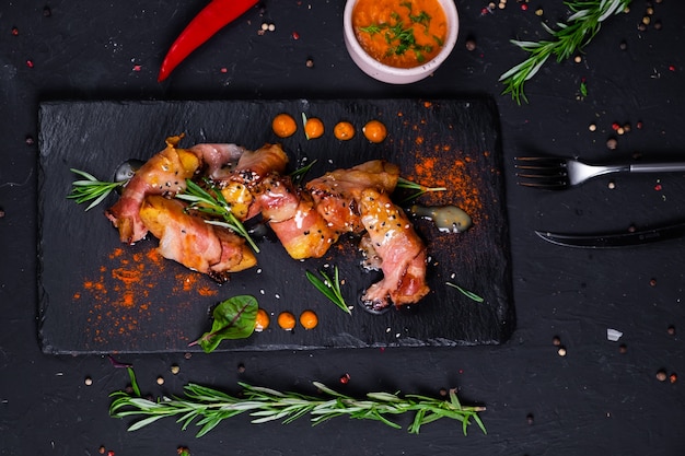 Gebackene Pellkartoffeln Speckscheiben mit Honig-Senf-Sauce auf einer dunklen Oberfläche