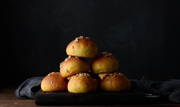 Gebackene runde Brötchen auf einem schwarzen Hintergrund des Holztischs Beschneidungspfad eingeschlossen