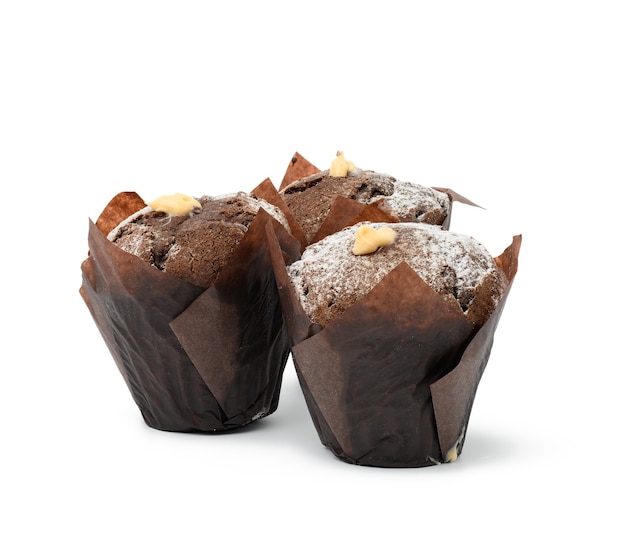 Gebackene Schokoladenmuffins mit Sahne in braunem Papier isoliert auf weißem Hintergrund