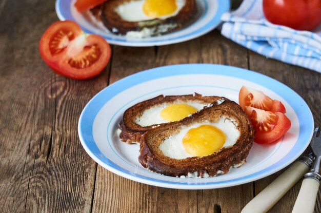 Gebackene Toasts mit Eierfüllung und Tomatenscheiben auf einem Teller