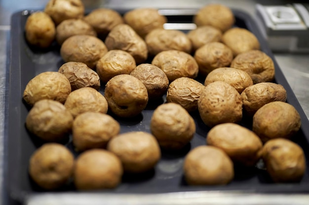 gebackene ungeschälte Kartoffeln auf einem Backblech Ofenkartoffel auf einem Backblech aus Metall und einem dunklen Hintergrund