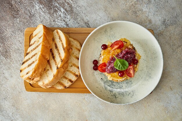 Gebackener Camembert-Käse mit Zwiebeln und Marmelade in einem Teller. Nahaufnahme, selektiver Fokus.