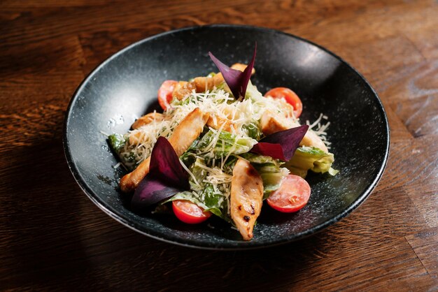 Gebackener Fischsalat mit Gemüse auf schwarzem Teller