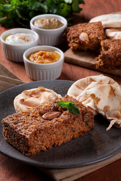 Gebackener Kebab mit Beilagen, Hummus, Babaganoush, Quark und Fladenbrot. Arabisches Essen.