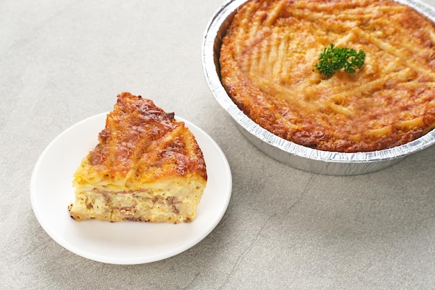 Gebackener Macaroni Schotel in einem Aluminiumfolienbecher auf grauem Hintergrund Ausgewählter Fokus