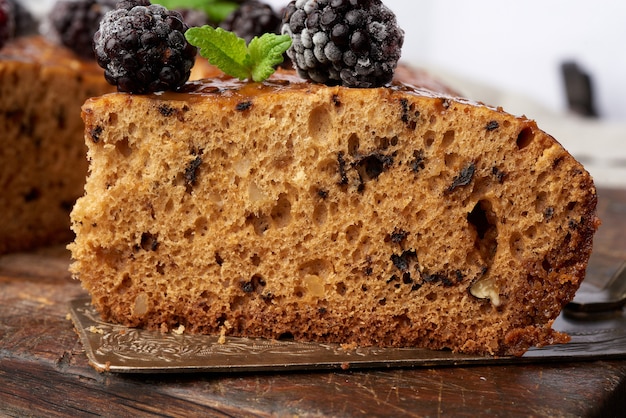 Gebackener runder Biskuitkuchen mit Nüssen und Beeren, brauner Holztisch