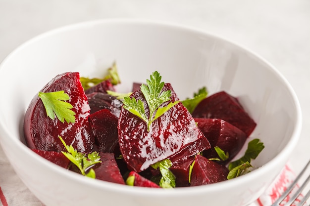 Gebackener Salat der roten Rübe mit Petersilie und Öl in einer weißen Schüssel.