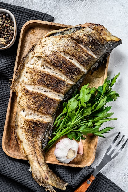 Gebackener Schellfisch aus ganzem Fisch auf einem Schneidebrett. Grauer Hintergrund. Draufsicht