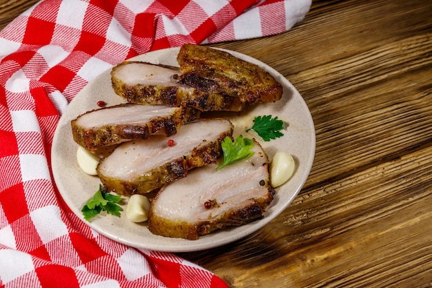 Gebackener Schweinebauch in einem Teller auf Holztisch