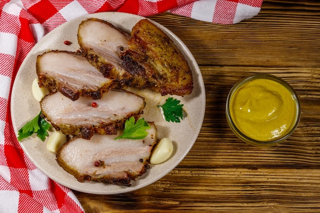 Gebackener Schweinebauch in einer Platte auf Holztisch Draufsicht