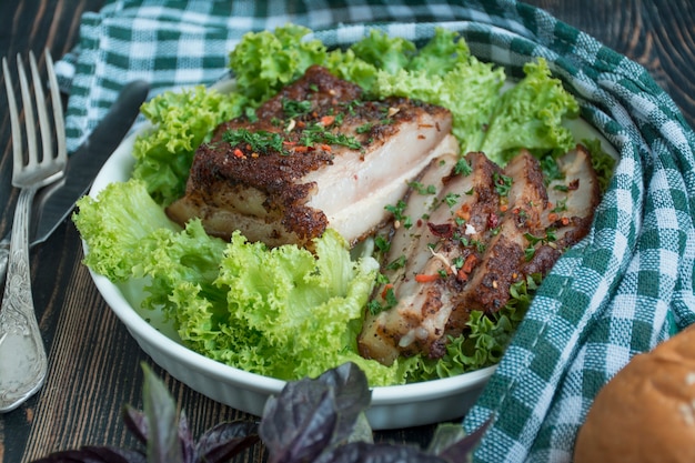 Gebackener Schweinebauch mit Gewürzen. Geschnittene Brust mit Gemüse serviert. Traditionelles Gericht der Ukraine. Nahansicht. Platz für Text.