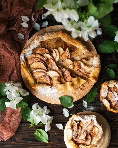 Gebackener süßer Apfelkuchen mit Honig und Zimt auf einem Holztisch Frühlingskekse und ein blühender Apfel