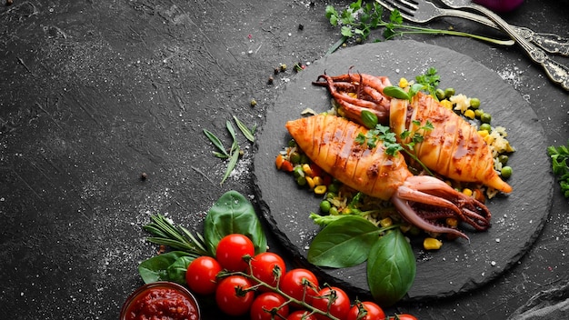 Gebackener Tintenfisch mit Reis und Gemüse auf einer schwarzen Steinplatte Draufsicht auf Meeresfrüchte Freier Kopierbereich