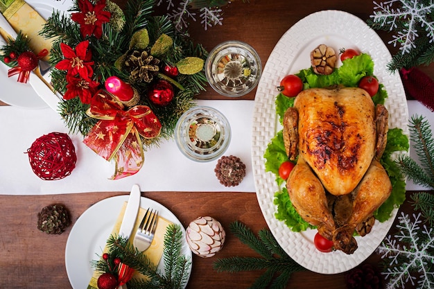 Gebackener Truthahn oder Huhn Der Weihnachtstisch wird mit einem mit hellen Schmuck und Kerzen geschmückten Truthahn serviert.