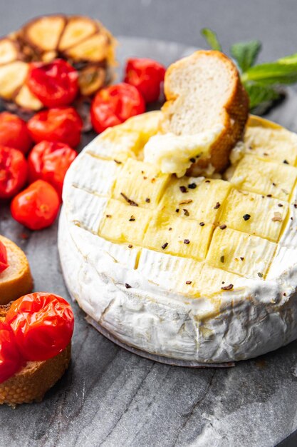 Gebackener Weichkäse Brie oder Camembert Tomate Knoblauch und Kräuter Mahlzeit Snack auf dem Tisch