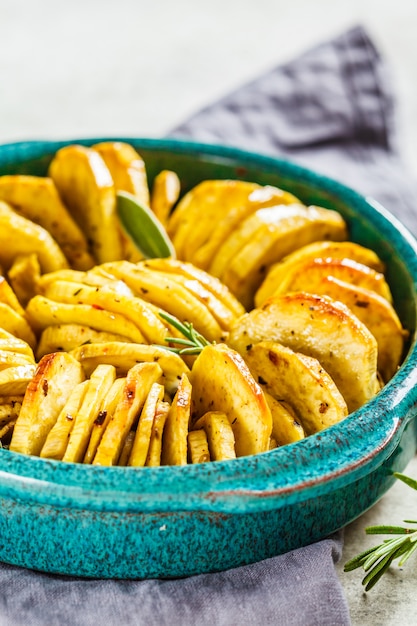 Gebackener weißer Süßkartoffelauflauf mit Kräutern im blauen Teller.