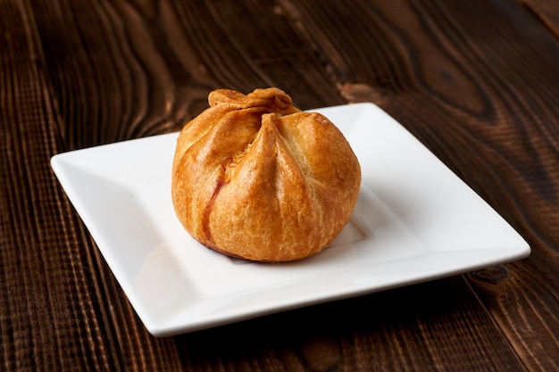 Gebackenes Brötchen auf Platte auf einem Holztisch