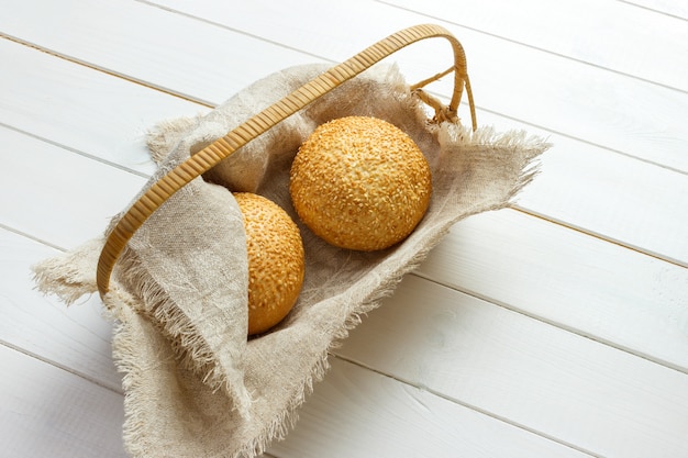 Gebackenes Brötchen mit dem Sesam seedsin Korb, der auf Gewebe liegt