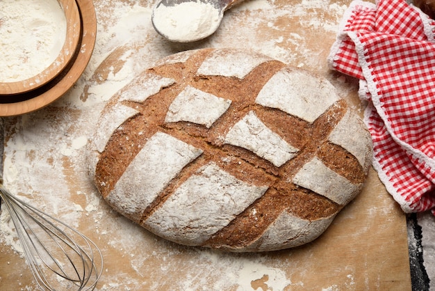 Gebackenes Brot auf dem Tisch und Zutaten, Küchenutensilien liegen in der Nähe, Draufsicht