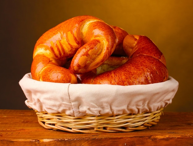 Gebackenes Brot im Korb auf einem Holztisch auf braunem Hintergrund