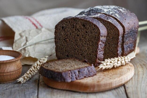 Gebackenes geschnittenes Brot mit Weizenähren auf Holztisch