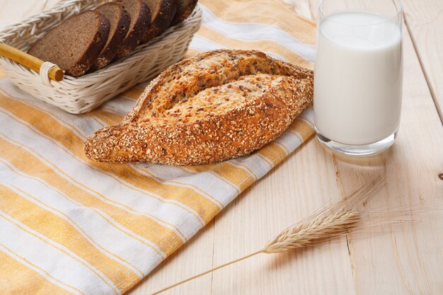 Gebackenes Getreidebrot mit Leinsamen mit Glas Milch auf Holztisch. Frühstückskonzept. Nahaufnahme