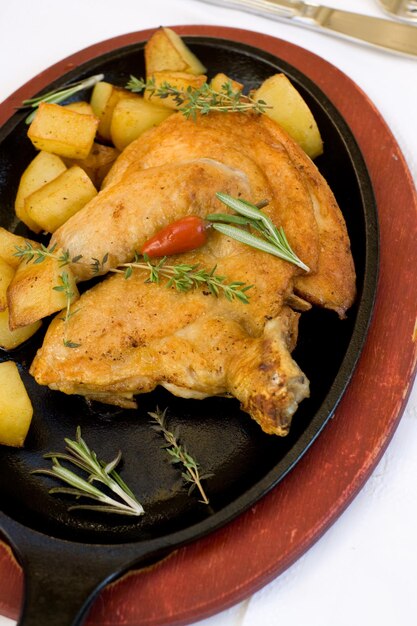 Foto gebackenes hähnchen mit kräutern auf einem schwarzen teller