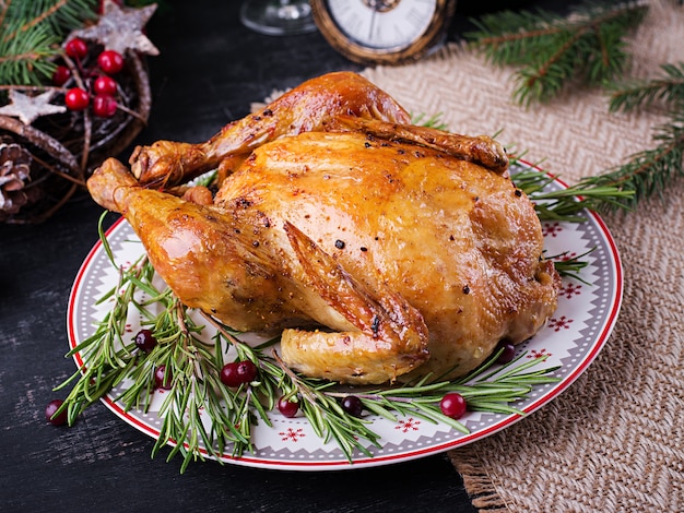 Gebackenes Hühnchen oder Truthahn. Der Weihnachtstisch wird mit Truthahn serviert, der mit hellem Lametta dekoriert ist. Gebratenes Huhn, Tisch. Weihnachtsessen. Sitzordnung bei Tisch. Ansicht von oben, oben