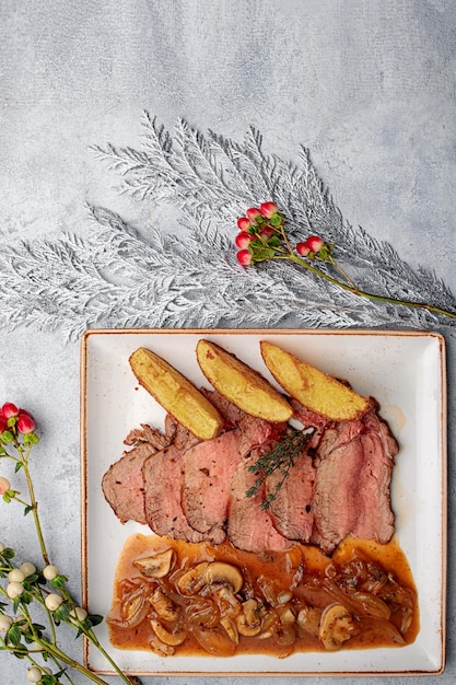 Gebackenes Kalbfleisch mit Kartoffeln und Champignons in vertikaler Sauce