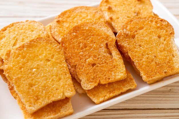 gebackenes knuspriges Brot mit Butter und Zucker auf Teller