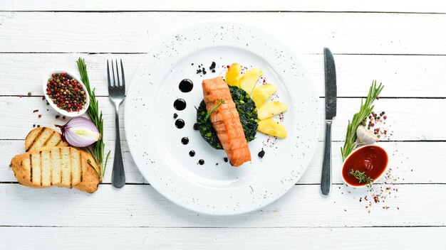 Gebackenes Lachsfilet mit Spinat und Apfel auf einem Teller Draufsicht Freier Kopierplatz