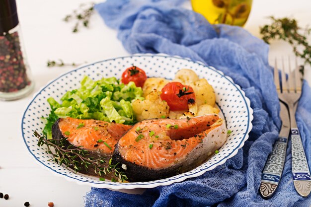 Gebackenes Lachssteak mit Blumenkohl, Tomaten und Kräutern. Richtige Ernährung.