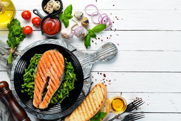 Gebackenes Lachssteak mit grünen Bohnen auf einer schwarzen Platte Draufsicht Freier Kopierplatz