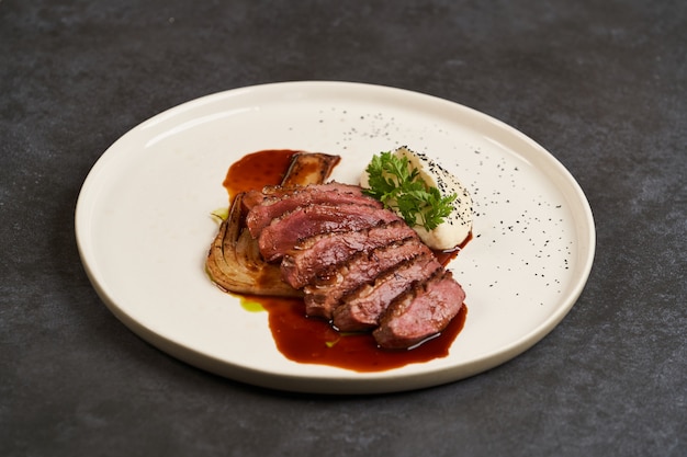 Gebackenes Putenfilet mit Selleriepüree und Sauce auf weißem Teller